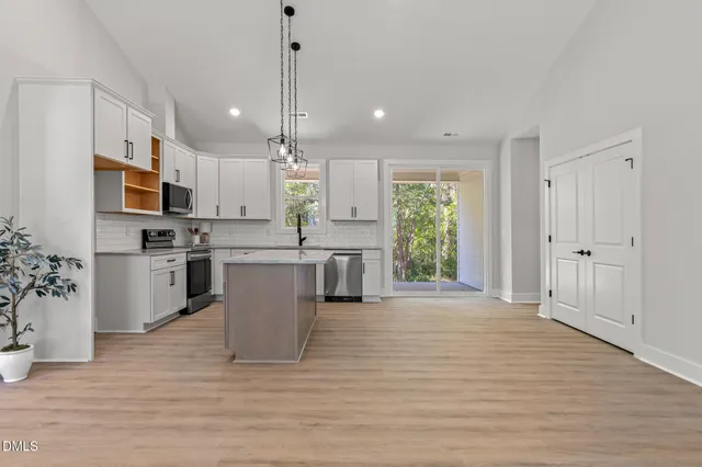 a large kitchen with kitchen island a large counter top stainless steel appliances and cabinets