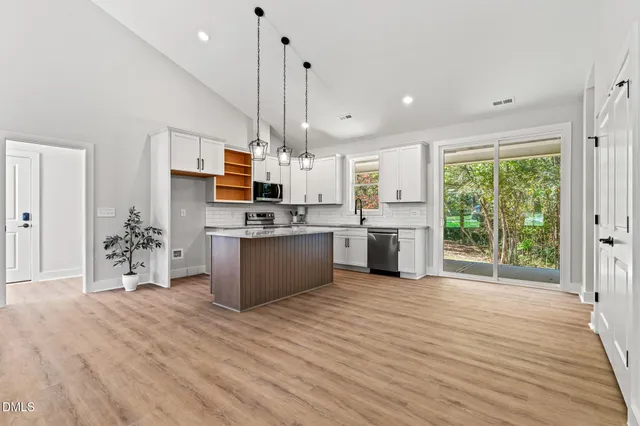 a large kitchen with stainless steel appliances kitchen island a large counter top a sink a stove and a wooden floors