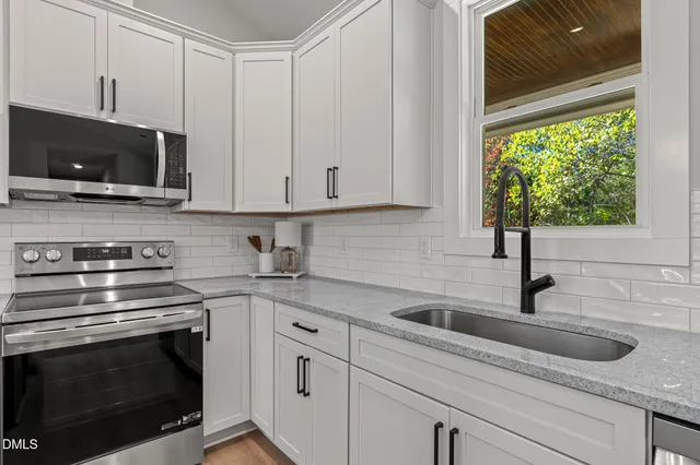 a kitchen with stainless steel appliances granite countertop white cabinets and a stove top oven