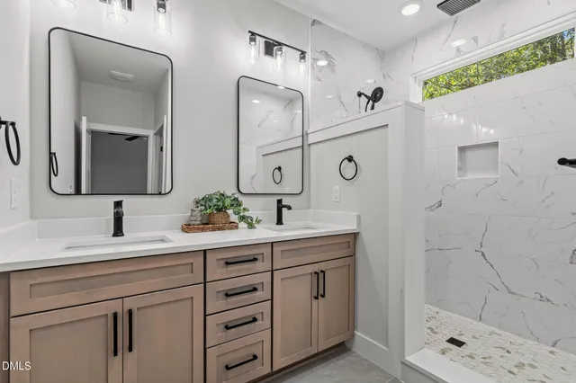 a bathroom with a double vanity sink mirror and shower