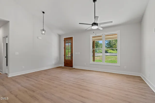 a view of an empty room with a window and wooden floor