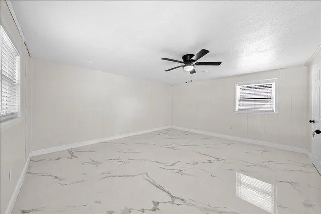 an empty room with a window and a ceiling fan