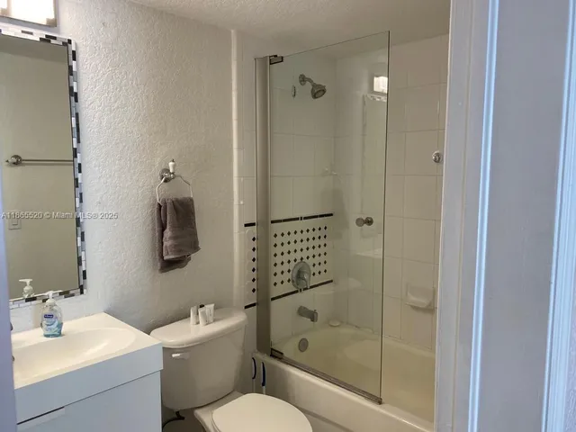 a bathroom with a bathtub shower sink vanity and toilet