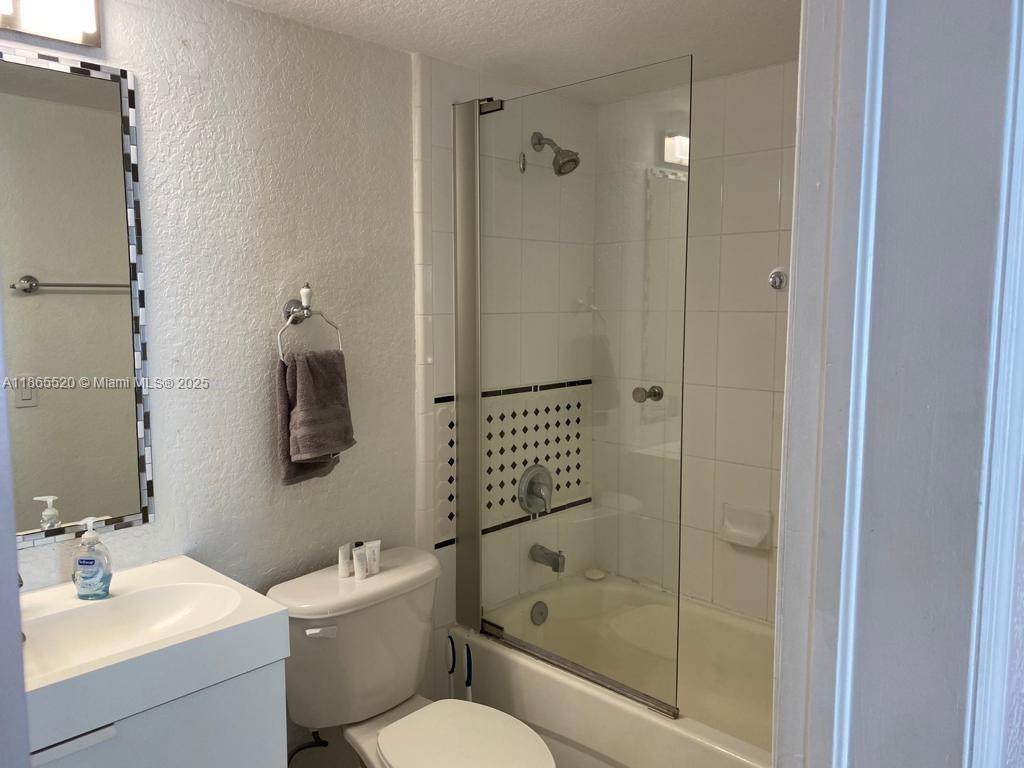 7326 Collins Avenue, Unit 105 Miami Beach, FL 33141 - Photo 11 of 13 a bathroom with a bathtub shower sink vanity and toilet