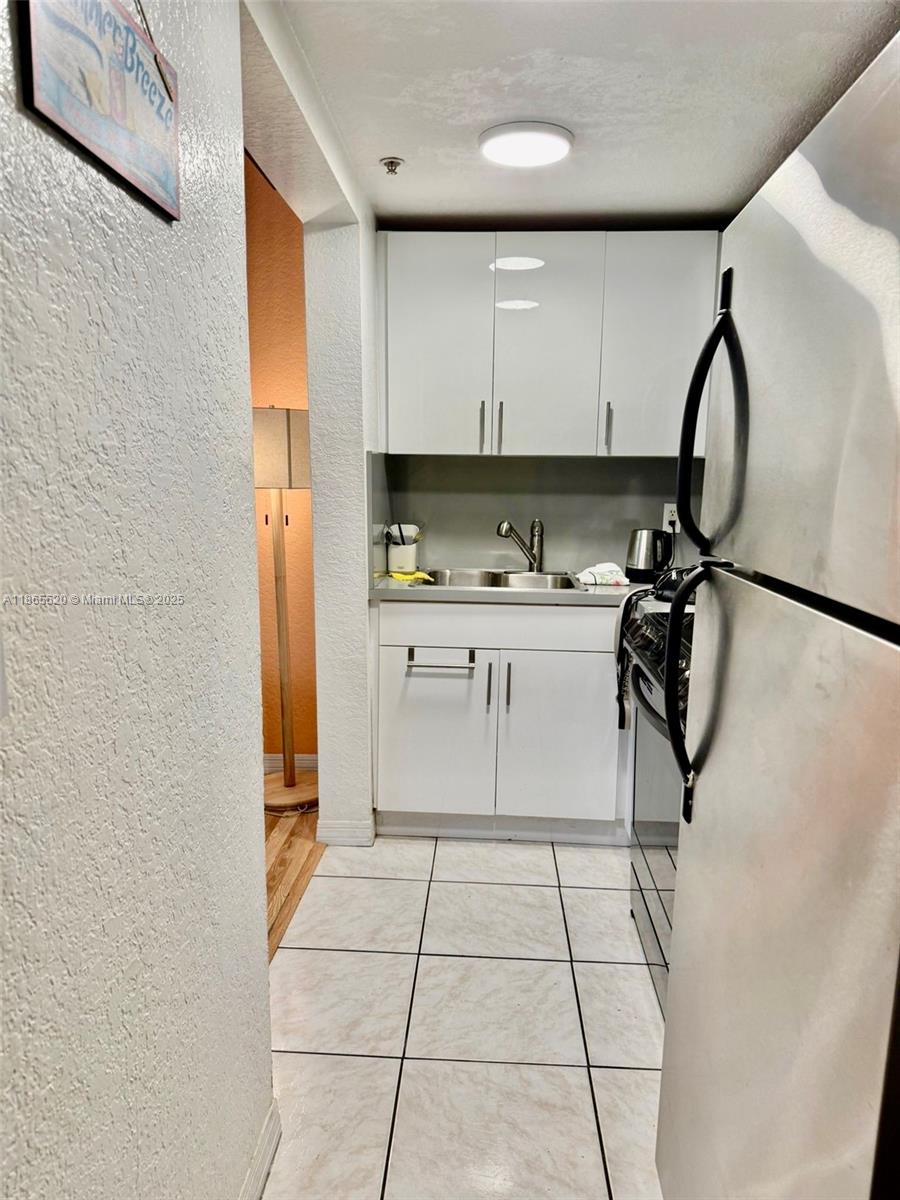 7326 Collins Avenue, Unit 105 Miami Beach, FL 33141 - Photo 9 of 13 a kitchen with a sink a refrigerator and cabinets