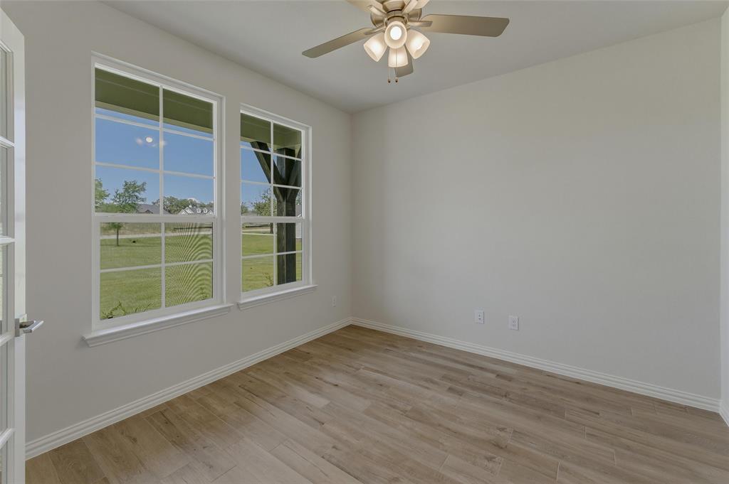 156 Oak Grv Way Springtown, TX 76082 - Photo 12 of 25 Room featuring light wood-finish flooring, two large multi-pane windows, a ceiling fan with integrated lighting, and white baseboards