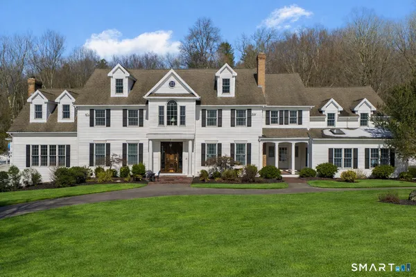 a front view of a house with a garden and trees