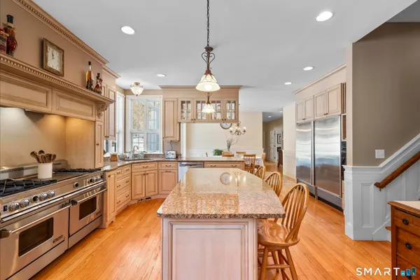 a large kitchen with stainless steel appliances granite countertop a stove a sink dishwasher a dining table and chairs with wooden floor