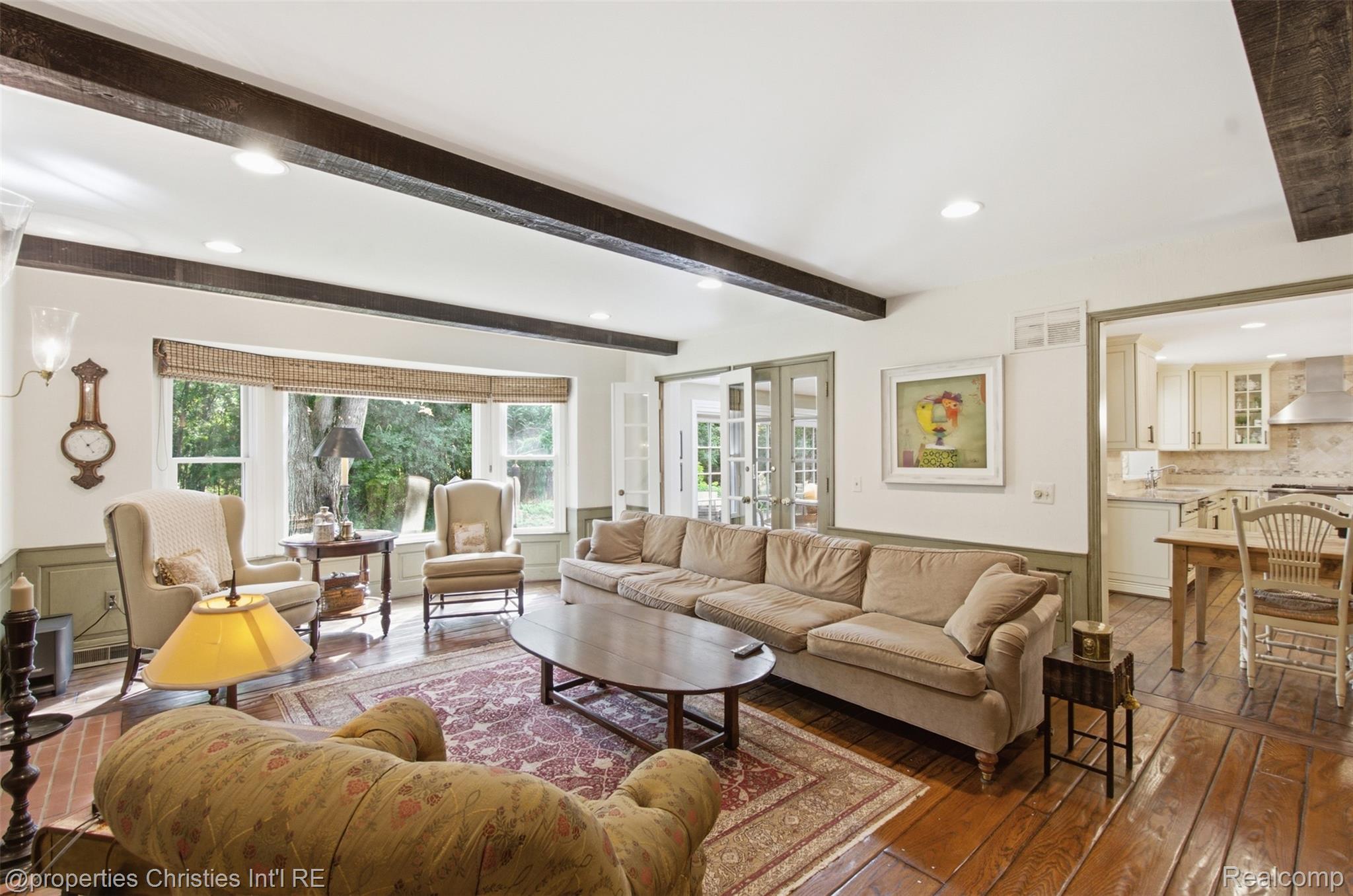 25235 Canterbury Road Franklin, MI 48025 - Photo 13 of 56 Great room featuring exposed ceiling beams, a large bay window, wide plank wood flooring, wainscoting, and recessed lighting