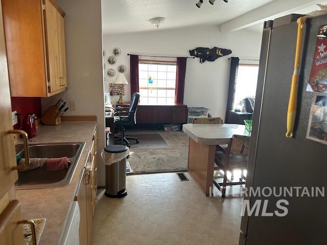 656 Liberty Lane Emmett, ID 83617 - Photo 22 of 31 Kitchen featuring freestanding refrigerator, vaulted ceiling, light countertops, white dishwasher, and wood finish cabinetry