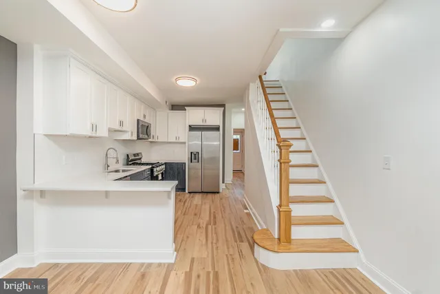 a kitchen with stainless steel appliances cabinets a sink and a wooden floor