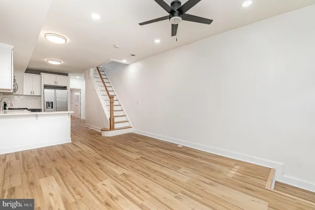 a view of an empty room with wooden floor and a ceiling fan