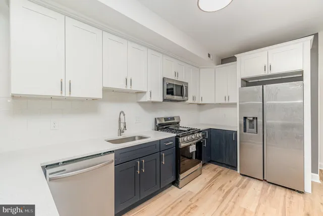 a kitchen with stainless steel appliances granite countertop a stove a sink dishwasher a refrigerator and a microwave oven with wooden floor