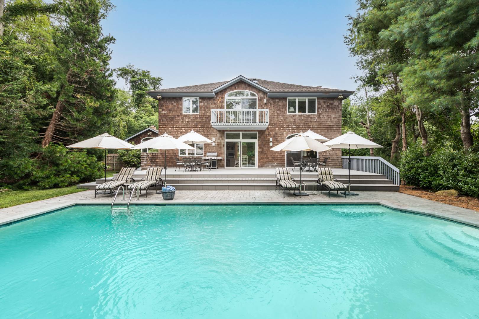 15 Atterbury Road Southampton, NY 11968 - Photo 1 of 20 a house with a garden and pool table and chairs under an umbrella