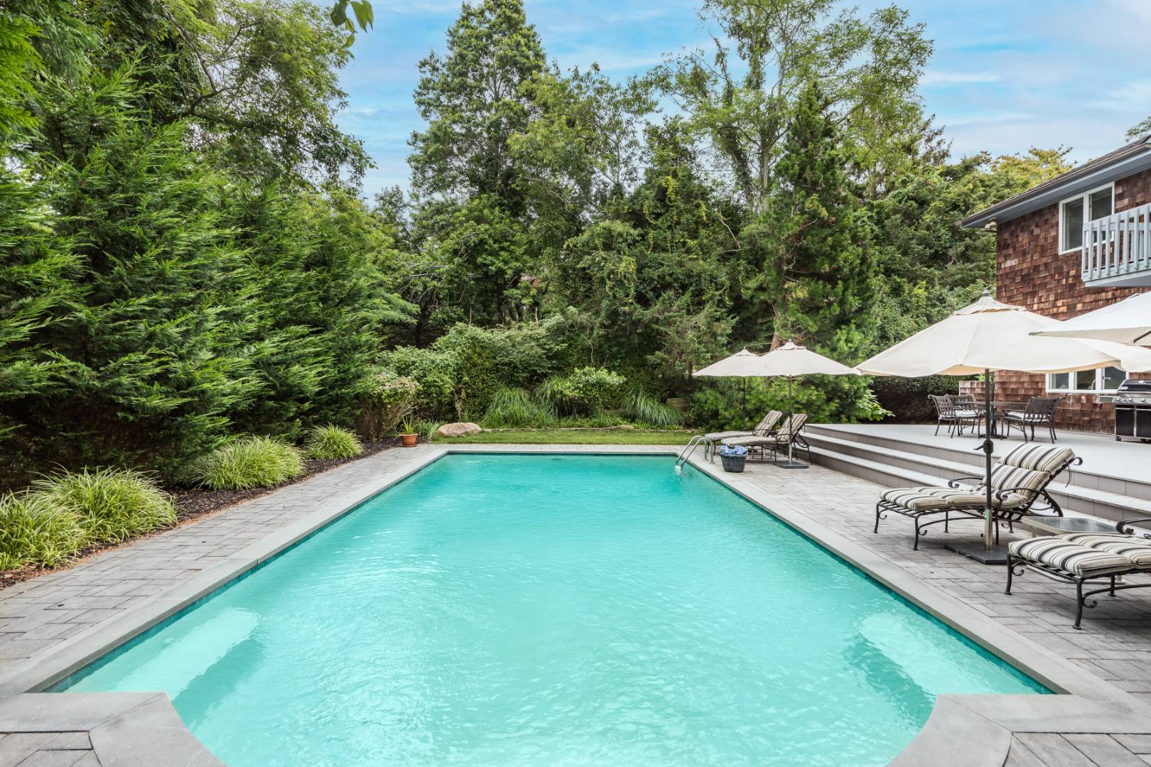 15 Atterbury Road Southampton, NY 11968 - Photo 20 of 20 a view of a swimming pool with lawn chairs under an umbrella