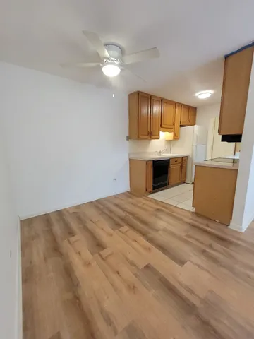 a view of kitchen and empty room with wooden floor