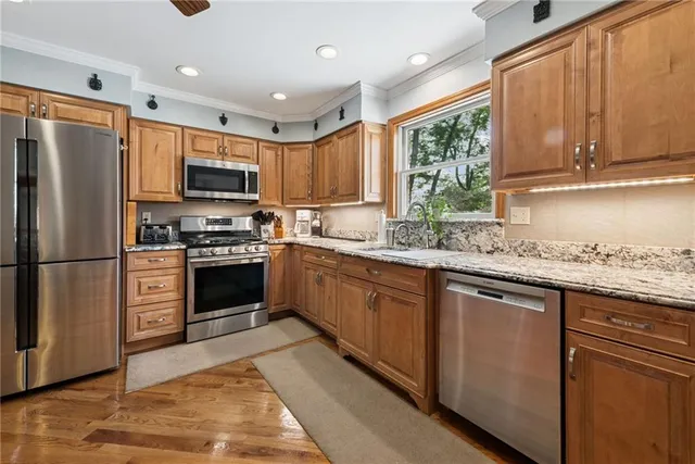 a kitchen with kitchen island granite countertop a sink appliances cabinets and a counter top space