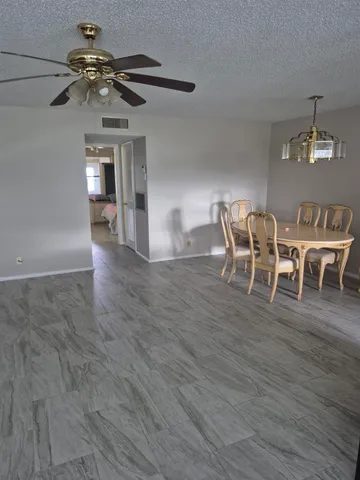 a dining room with wooden floor a chandelier a glass table and chairs