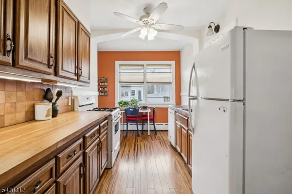 a kitchen with stainless steel appliances granite countertop a refrigerator a sink dishwasher a stove and white countertops with wooden floor