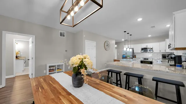 a kitchen with stainless steel appliances kitchen island granite countertop a refrigerator a stove and a wooden floors