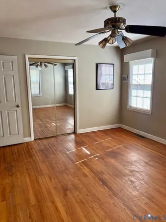 a view of an empty room with a window and wooden floor