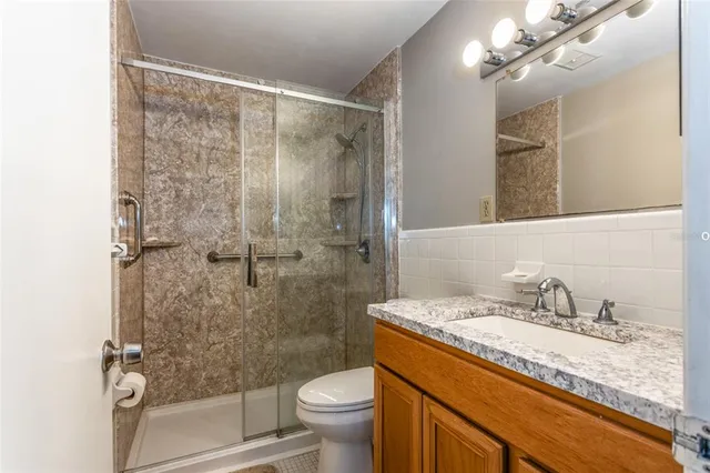 a bathroom with a granite countertop sink a toilet and shower