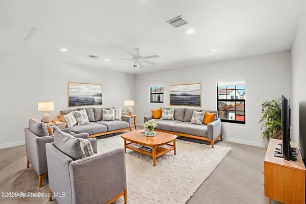 a living room with furniture potted plant and kitchen view