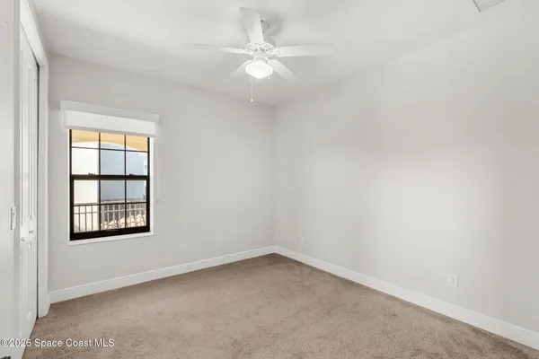 an empty room with closet and a ceiling fan