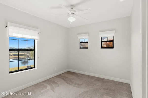 an empty room with a mirror and a ceiling fan