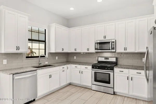 a kitchen with granite countertop white cabinets and white appliances