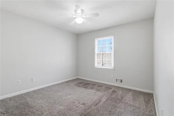 an empty room with a window and a fan