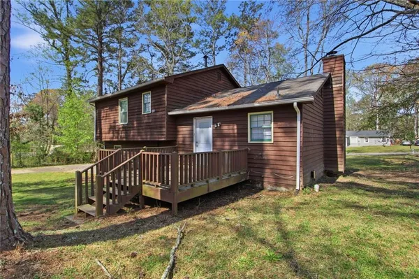 a view of a house with a wooden deck and a yard
