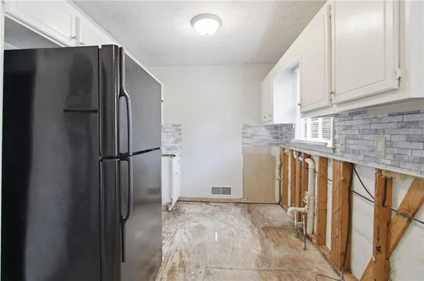 a view of a refrigerator in kitchen and wooden cabinets