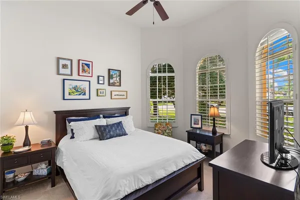 a bedroom with large bed and two windows