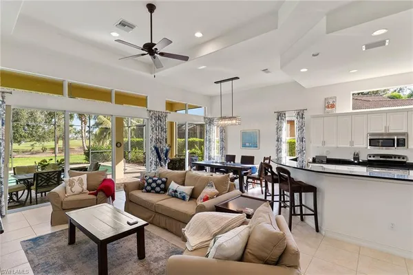 a living room with furniture kitchen area and a large window