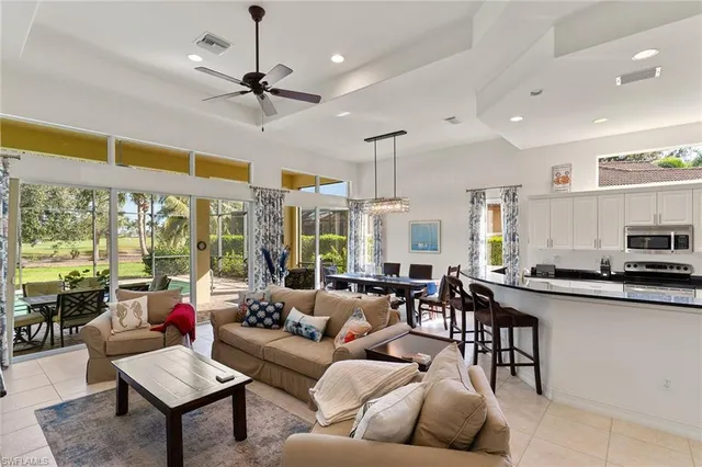 a living room with furniture kitchen area and a large window