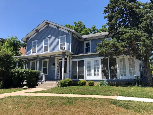 a front view of a house with a yard and potted plants