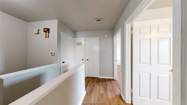 a view of a hallway with wooden floor and staircase