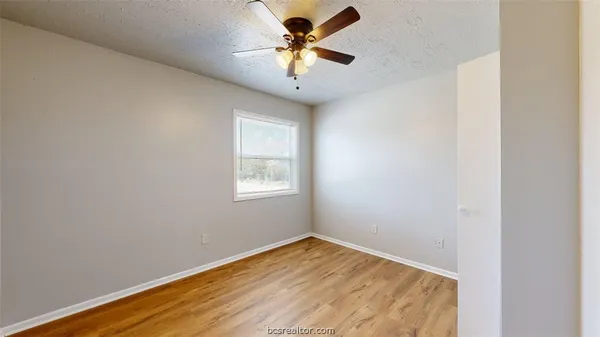 an empty room with a window and a chandelier fan