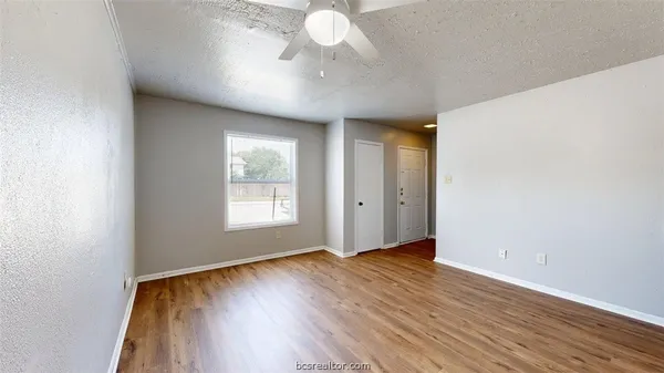 a view of an empty room with wooden floor and a window