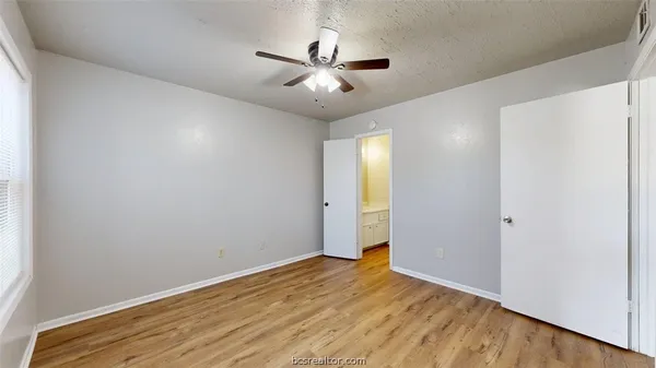 an empty room with wooden floor and ceiling fan
