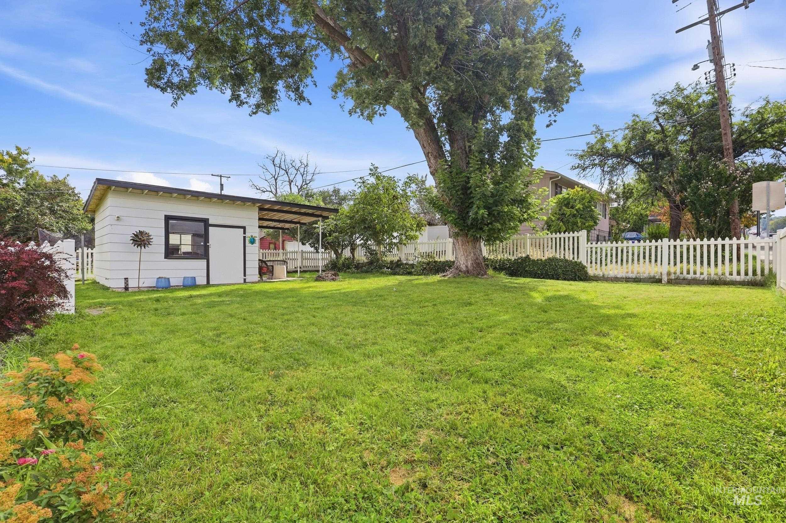 1803 14th Street Lewiston, ID 83501 - Photo 24 of 27 Expansive grassy yard featuring a white picket fence, a dedicated storage shed, and mature trees