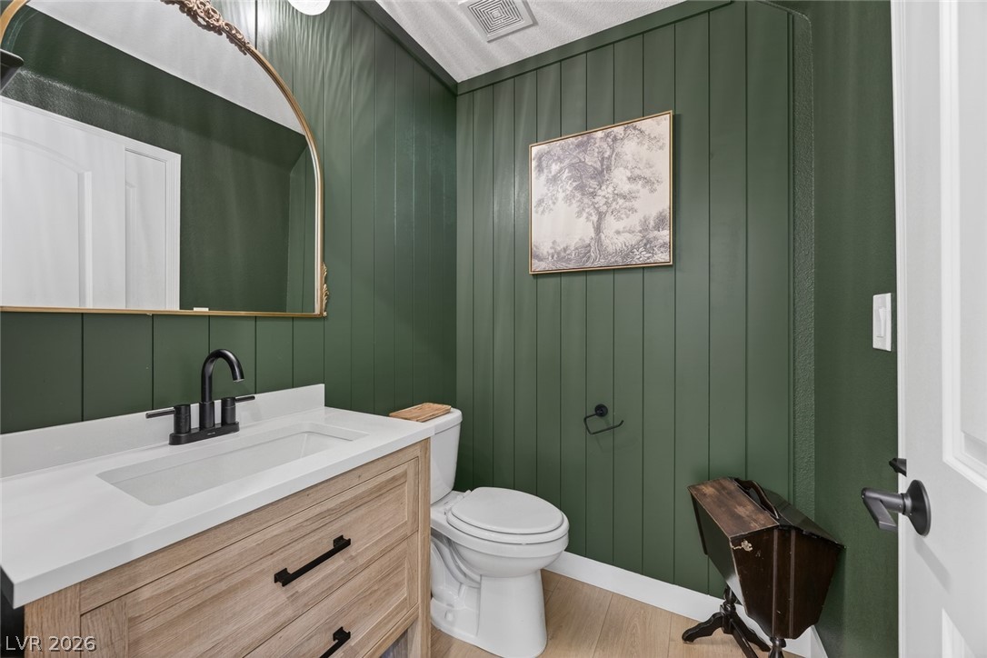 10446 Emerald Rye Street Las Vegas, NV 89183 - Photo 17 of 37 Elegant powder room featuring a modern vanity with a single basin, complemented by rich paneled walls.