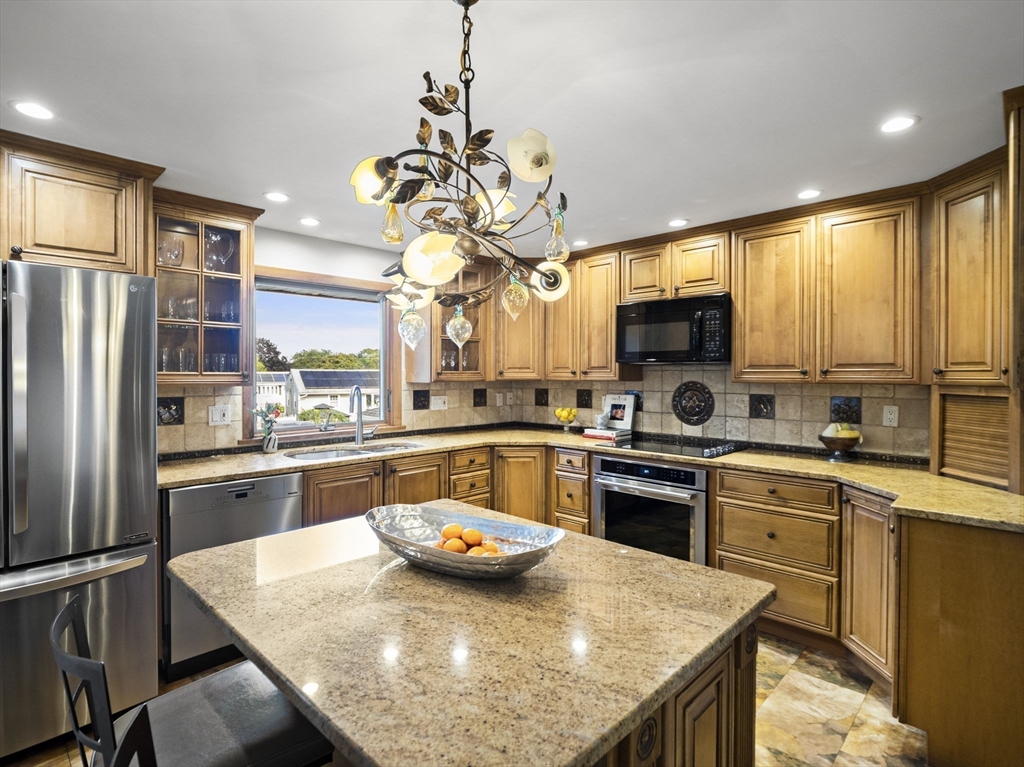 15 North Street Andover, MA 01810 - Photo 17 of 42 a kitchen with kitchen island granite countertop stainless steel appliances a sink stove and refrigerator