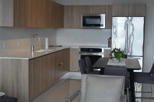 a kitchen with stainless steel appliances a sink a microwave a refrigerator and a stove