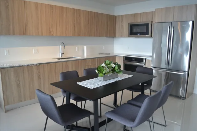 a kitchen with stainless steel appliances a dining table chairs and a refrigerator