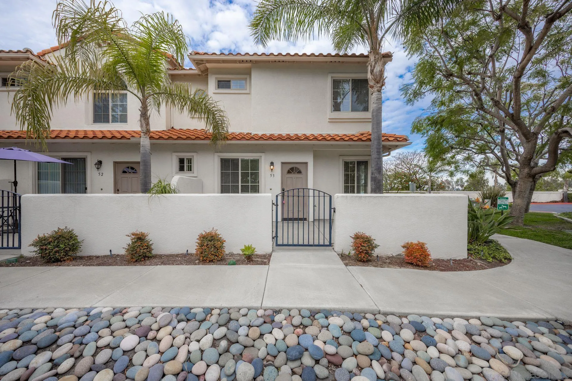 4058 Craven Road, Unit 53 Oceanside, CA 92057 - Photo 1 of 31 a view of a white house with large windows and a table and chair