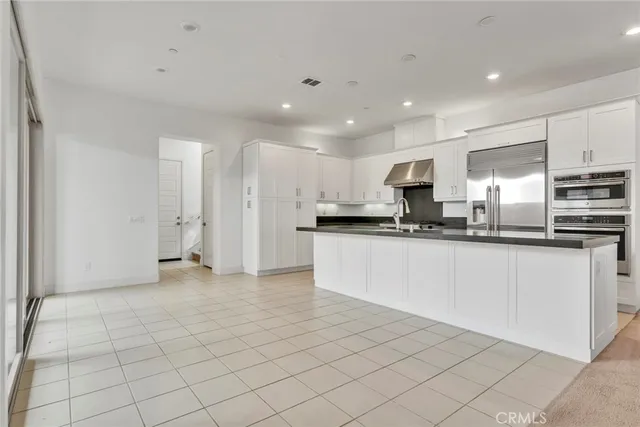 a large white kitchen with a stove a sink a microwave and cabinets