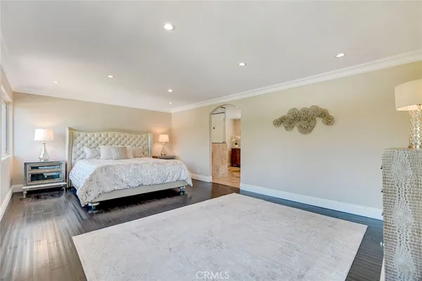 a bedroom with a bed and a large mirror with wooden floor