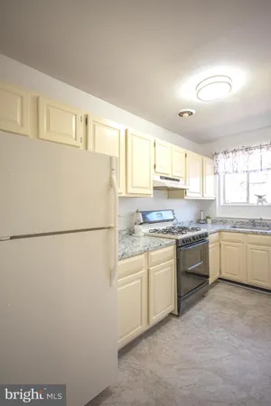 a kitchen with granite countertop a refrigerator sink stove and oven